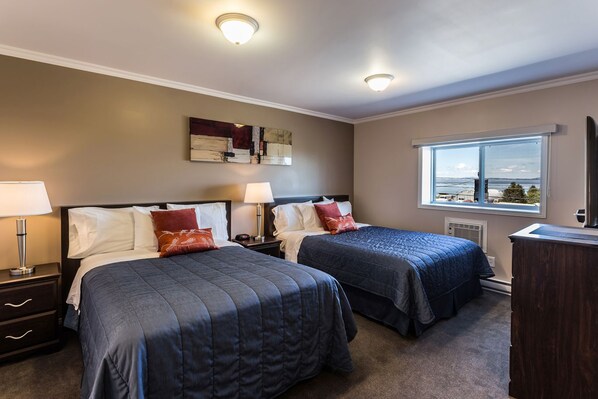 Une chambre d’hôtel avec deux lits, une grande fenêtre donnant sur un beau paysage et un luminaire au plafond.