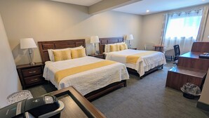 Een hotelkamer met twee bedden, een bureau, een stoel en een afvalbak.