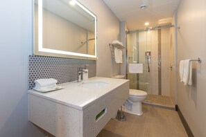 A modern bathroom with a large mirror, a sink, and a glass-enclosed shower. - Motel RDL au vieux piloteux (Rivière-du-Loup)