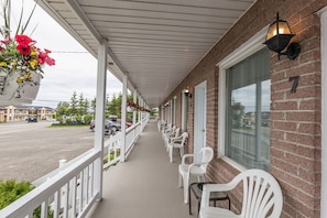Un motel doté d’une véranda, de chaises blanches et de jardinières suspendues.