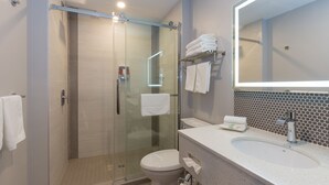 Een moderne badkamer met een douchecabine, een toilet, een wastafel met spiegel en handdoeken op een rek.