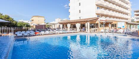 Una piscina al aire libre, sillones reclinables de piscina