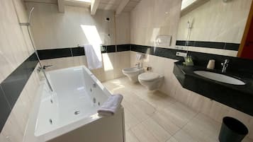 Een moderne badkamer met een badkuip, toilet, bidet en wastafel.