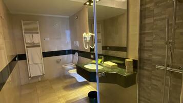 Un baño moderno con ducha de vidrio, lavabo con espejo y toallero.