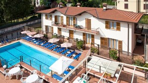 A hotel with a swimming pool, outdoor seating, and a terrace with umbrellas. - Albergo Lenno (Tremezzina)