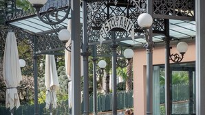 An outdoor cafe with wrought iron furniture, a covered seating area, and a sign reading "Restorante". - Albergo Lenno (Tremezzina)