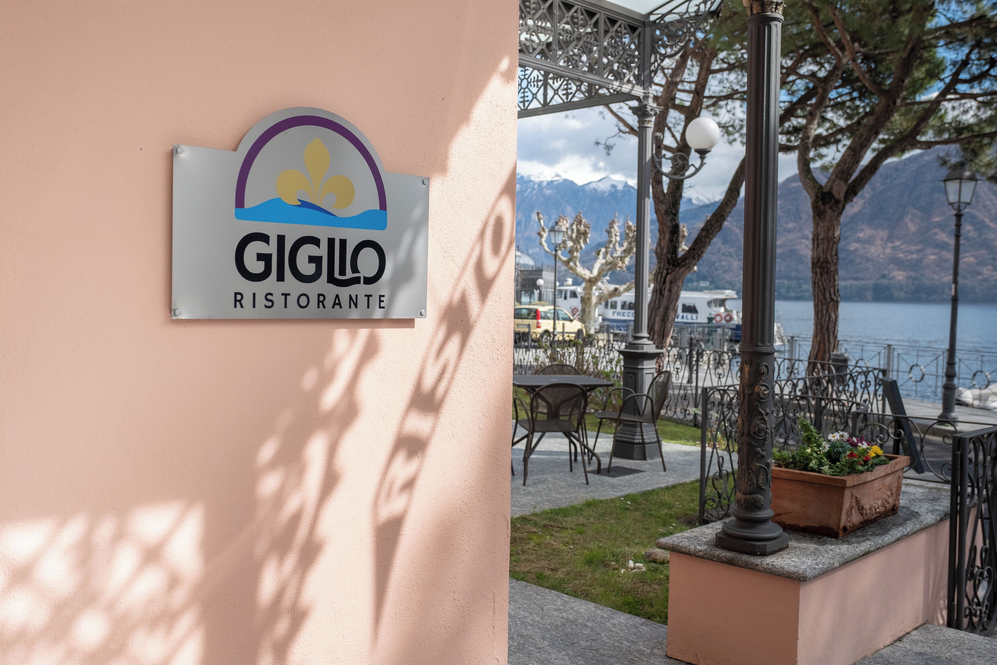 A sign for 'GIGLO RISTORANTE' with a view of a lakeside patio area.