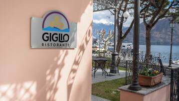 A sign for 'GIGLO RISTORANTE' with a view of a lakeside patio area.