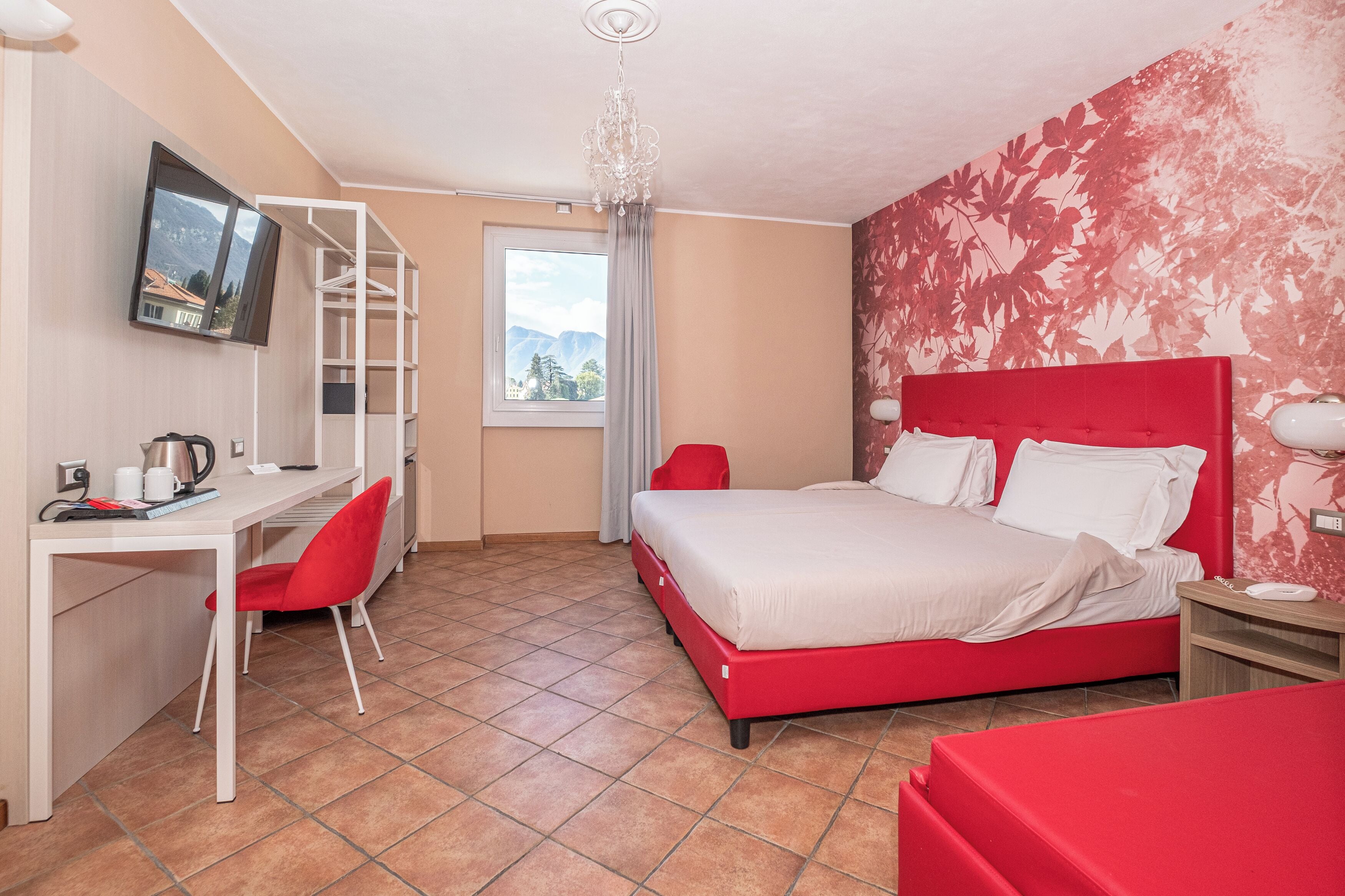 A hotel room with a bed, desk, chair, and a TV on the wall.