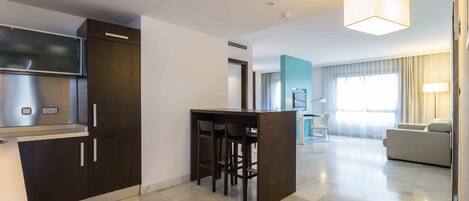 A modern kitchen with dark cabinetry, a central island with stools, and a dining area with a table and chairs.