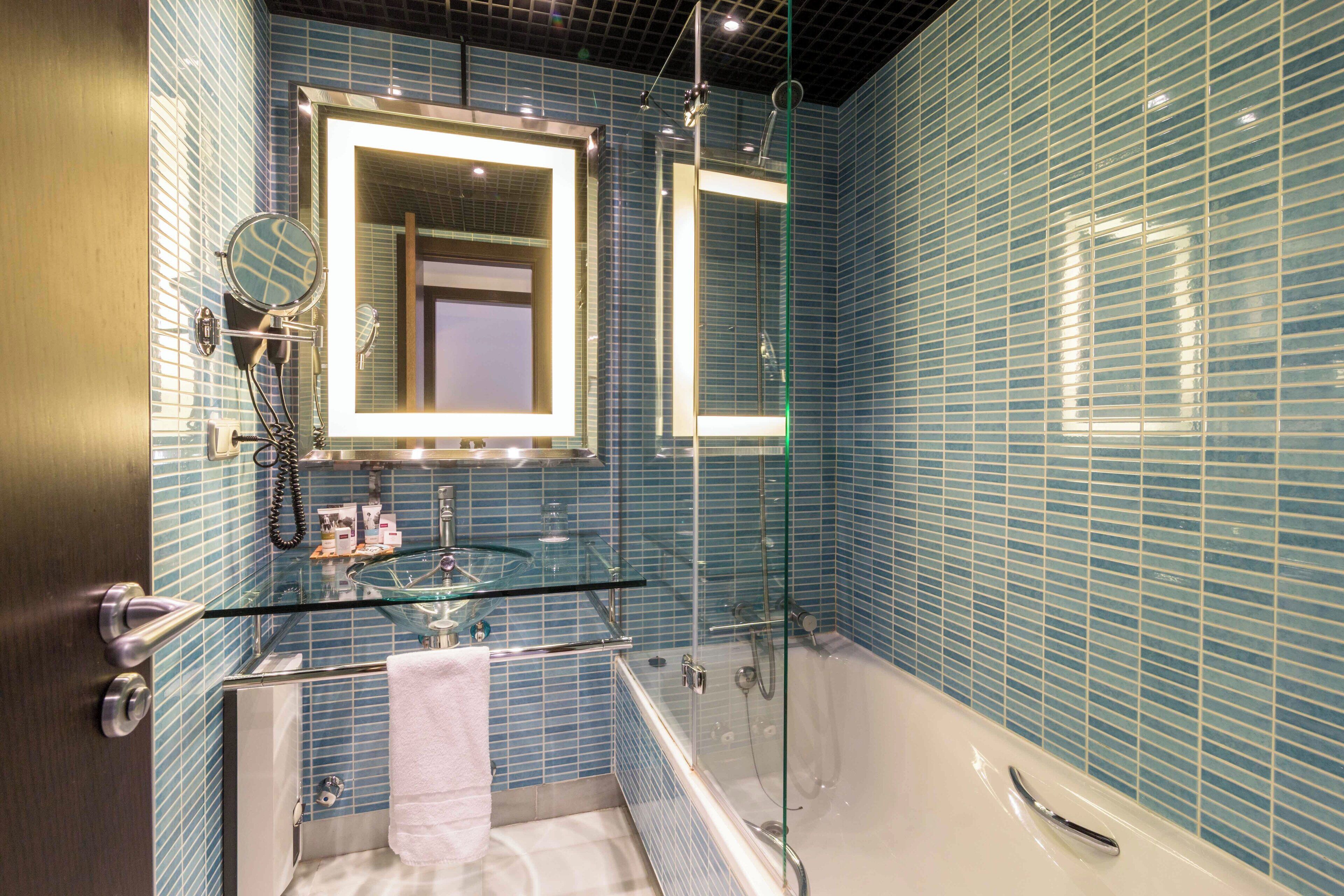 Un baño moderno con cabina de ducha de vidrio, un espejo grande y una bañera.