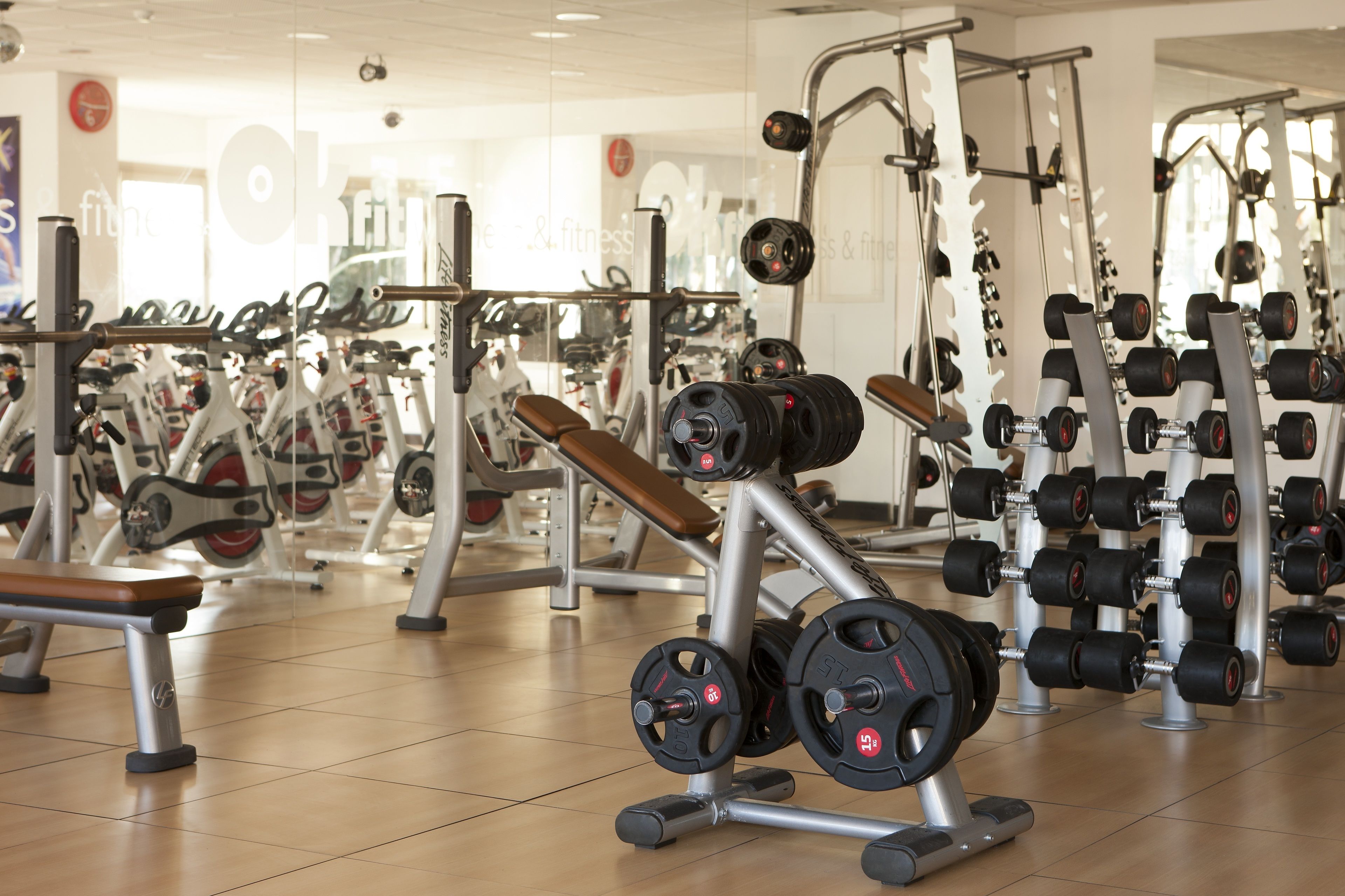 Un gimnasio con diversos equipos de ejercicio, incluyendo mancuernas y bancos.