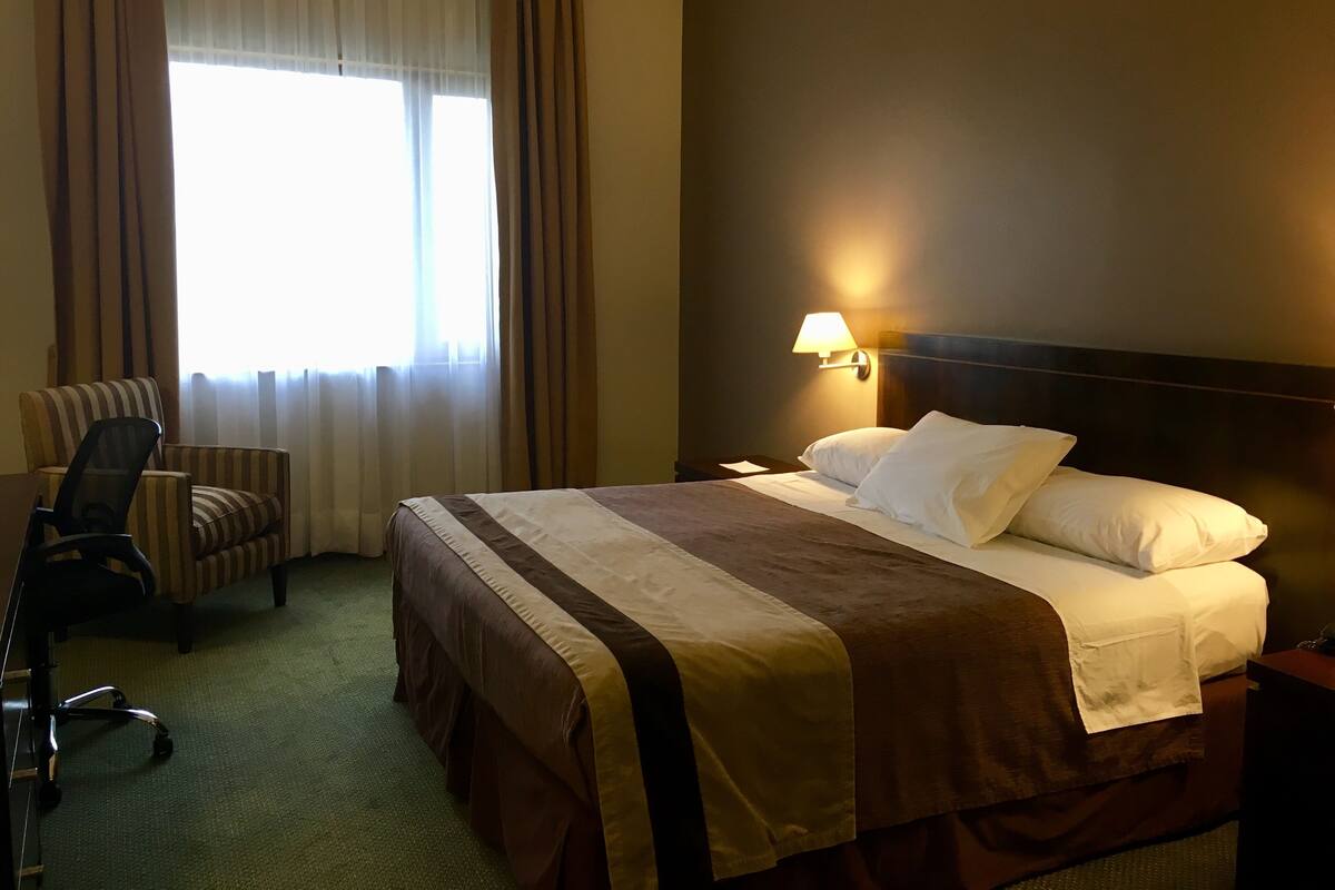 Une chambre d’hôtel avec un lit, une chaise, un bureau et une lampe.