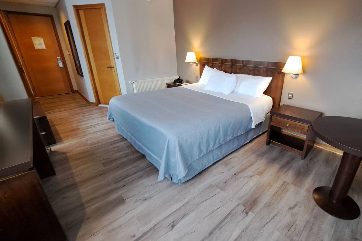 Une chambre d’hôtel comprenant un lit, des tables de chevet, un bureau et une chaise.