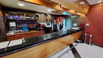 A bar area with a counter, shelves with bottles, and a red Coca-Cola fridge.