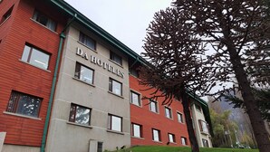 Un edificio con el letrero 'DA Hoteles', que indica un hotel. Tiene fachada roja y beige con varias ventanas.