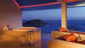 Ein moderner Spa-Bereich mit einer großen Badewanne, einem Massagetisch und Blick auf den Ozean.