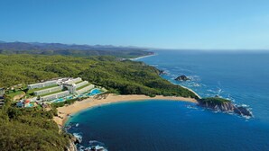 Ein Resort mit mehreren Gebäuden, einem großen Schwimmbad und einem Strand.