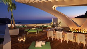 Ein moderner Außen-Loungebereich mit grünen Sitzgelegenheiten, einer Bar und Meerblick.