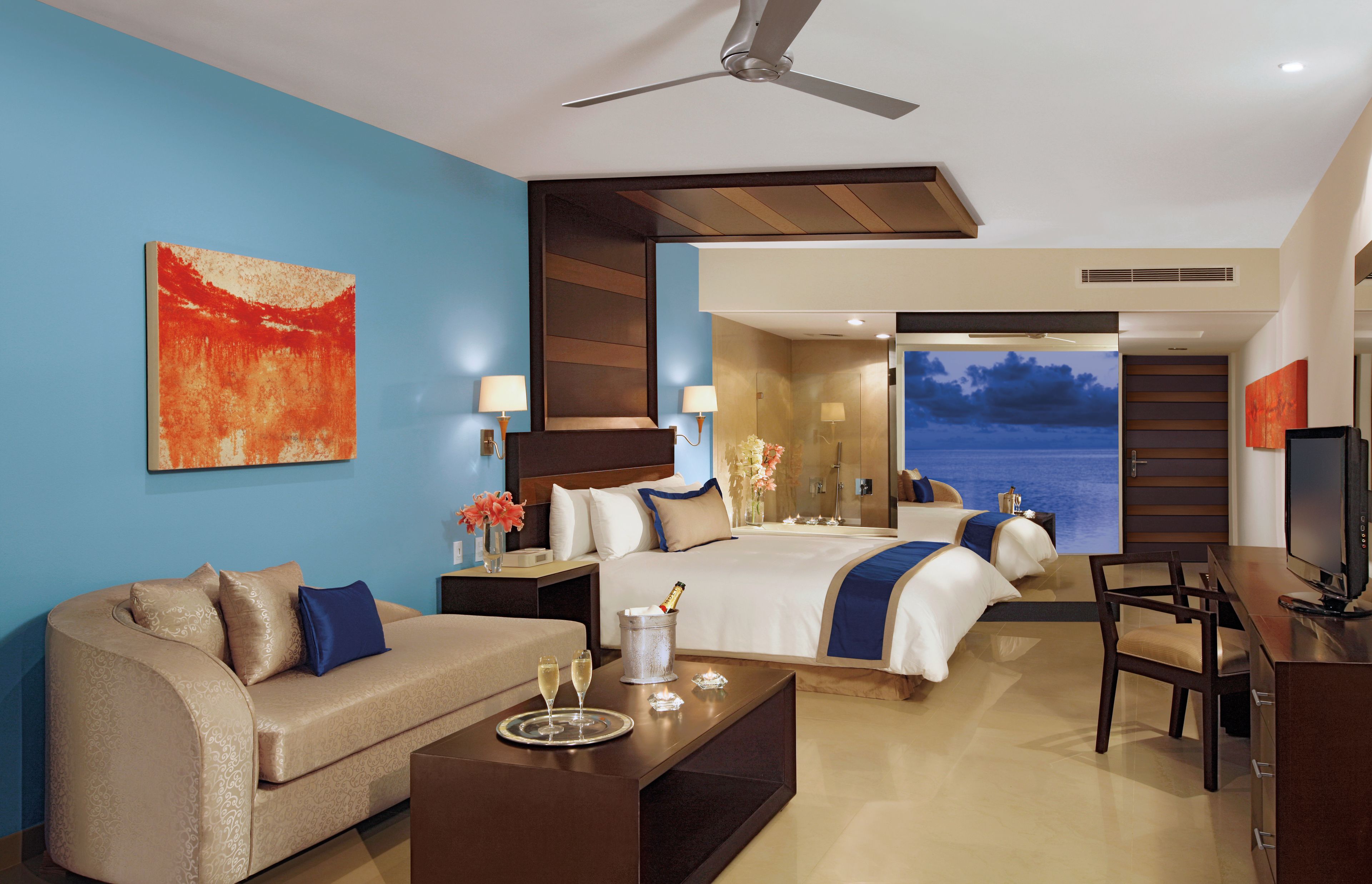 A modern hotel room with a bed, a sofa, a desk, and a television.