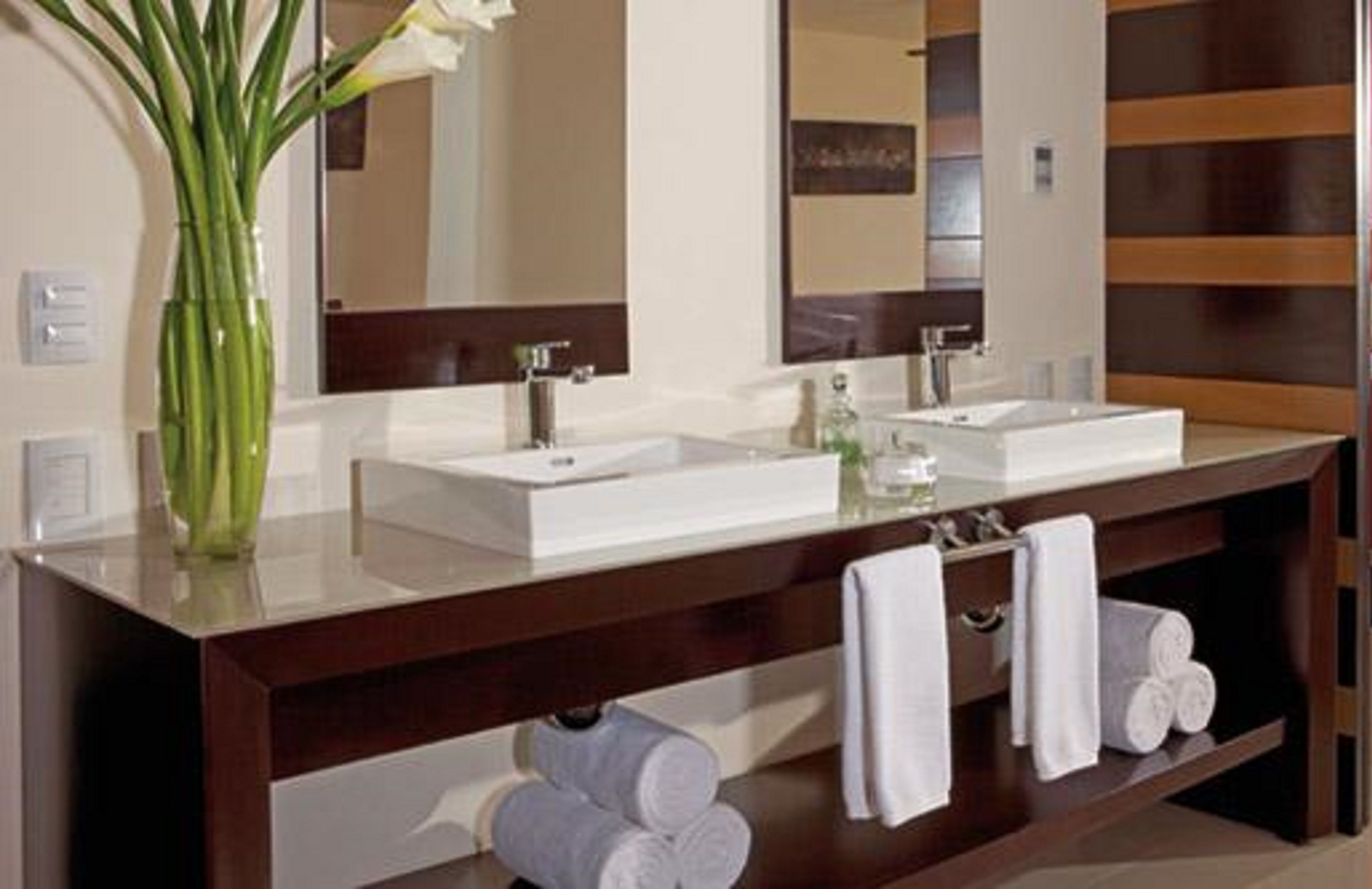 A modern bathroom with two sinks, a large mirror, and a dark wooden vanity.