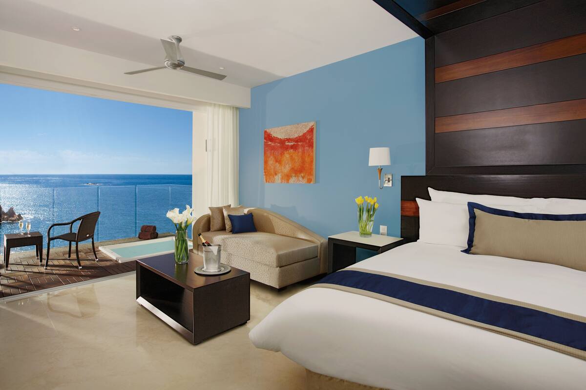 Ein Hotelzimmer mit Bett, einer Couch, einem Couchtisch und Blick aufs Meer.