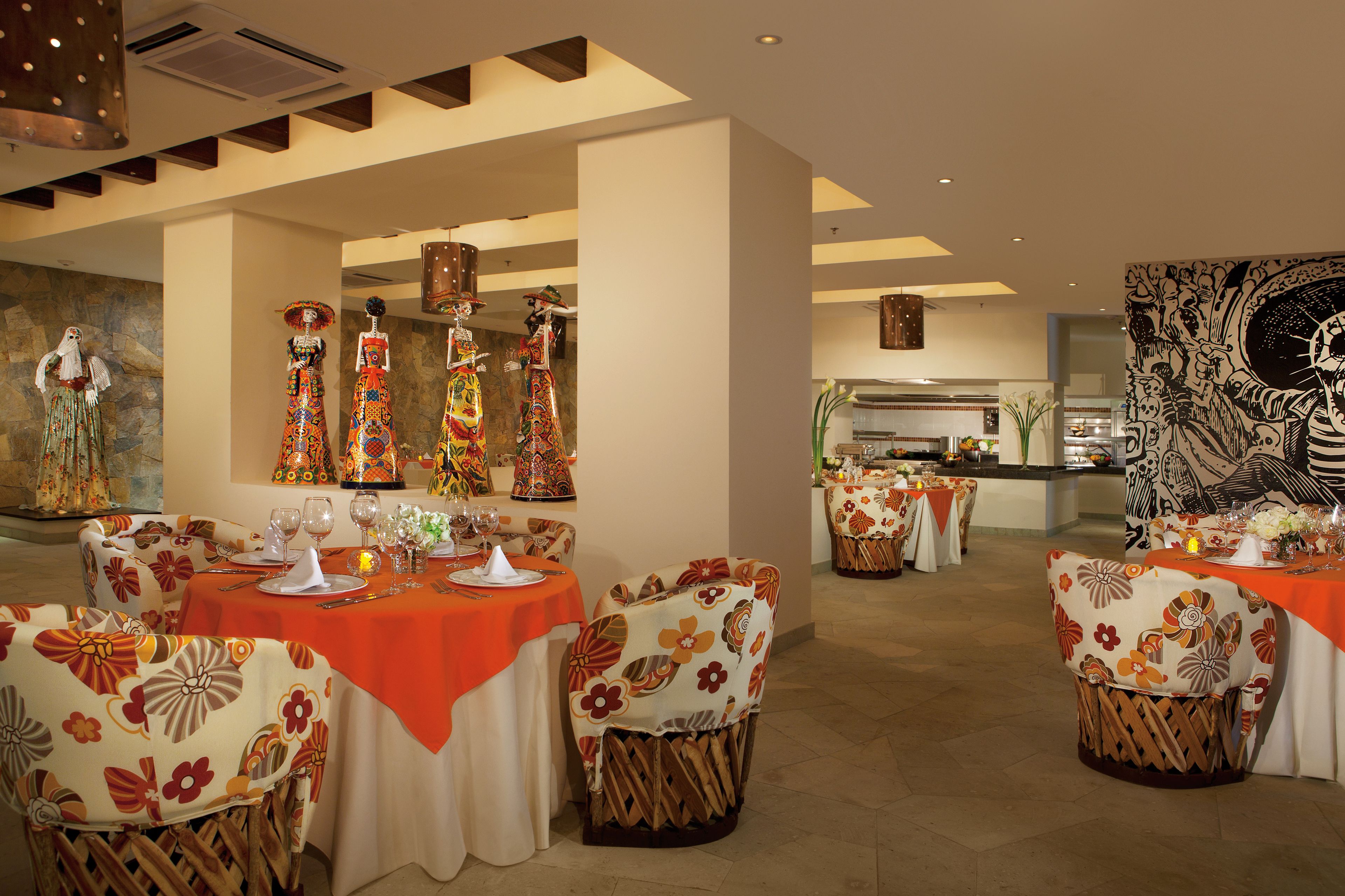 A restaurant with multiple tables and chairs, each covered with orange tablecloths and floral-patterned chairs.