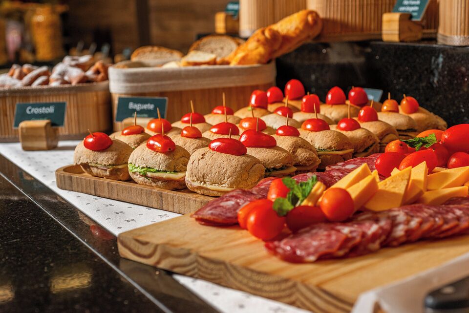 A buffet with various food items including sandwiches, cheese, and cured meats.