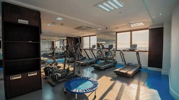 Un gimnasio moderno con cintas de correr, máquinas elípticas y un trampolín.