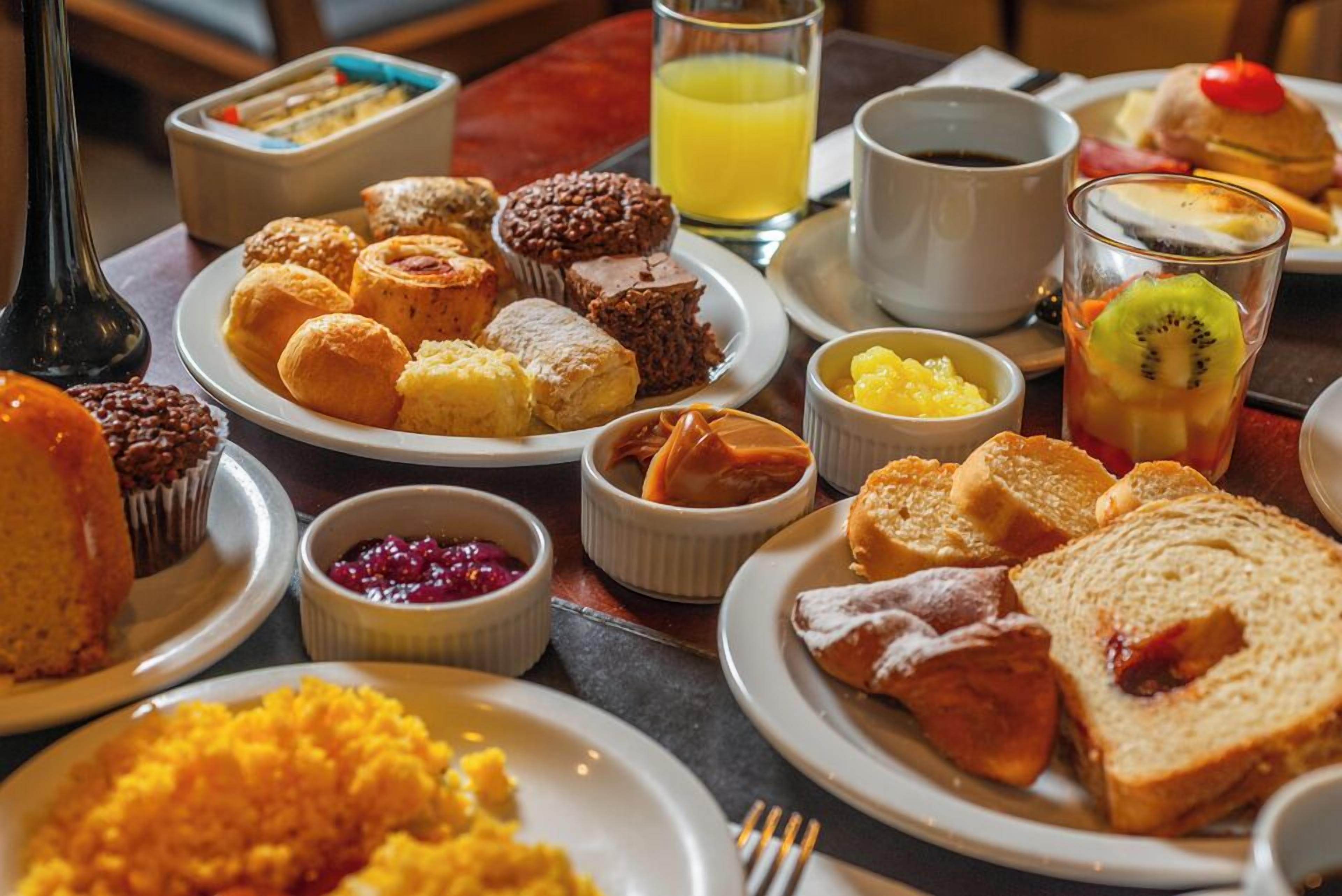 A breakfast buffet with various pastries, fruits, and beverages.