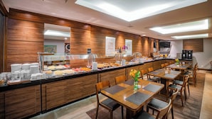 A modern breakfast area with a long counter, buffet, and seating area. - Laghetto Bento (Bento Gonçalves)