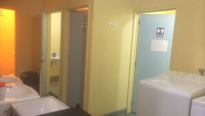 A hotel bathroom with a sink, mirror, and a washing machine. - Racecourse Backpackers Hostel (Christchurch)