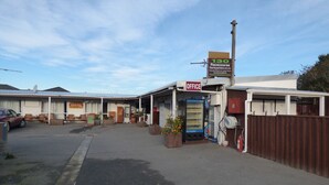 A hotel with a sign for the office and a racecourse. - Racecourse Backpackers Hostel (Christchurch)