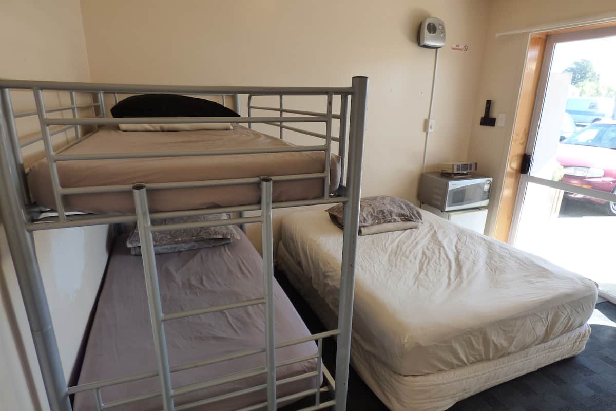 A bunk bed room with a microwave and a no smoking sign on the wall.