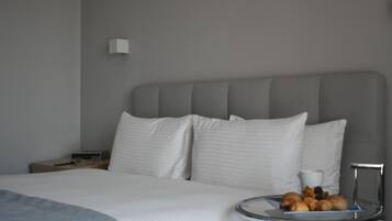 A hotel room with a large bed, a bedside table, a lamp, and a tray with pastries.