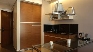 A modern kitchen with wooden cabinets, a glass dining table, and stainless steel appliances.