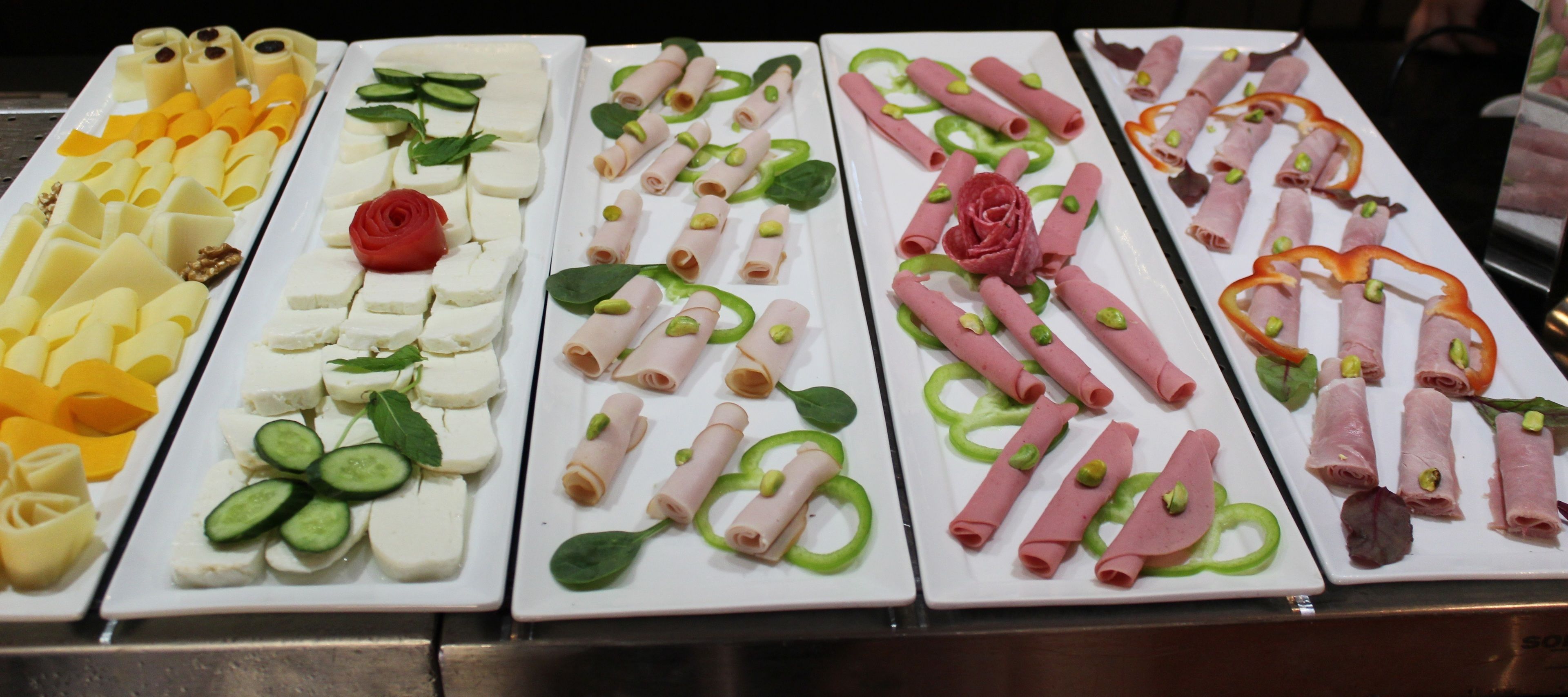 A buffet with various food items including cheese, rolls, and garnishes.