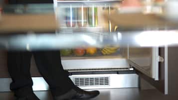 Une personne qui prépare et sert des aliments provenant d’un réfrigérateur rempli de fruits, de boissons et d’assaisonnements.