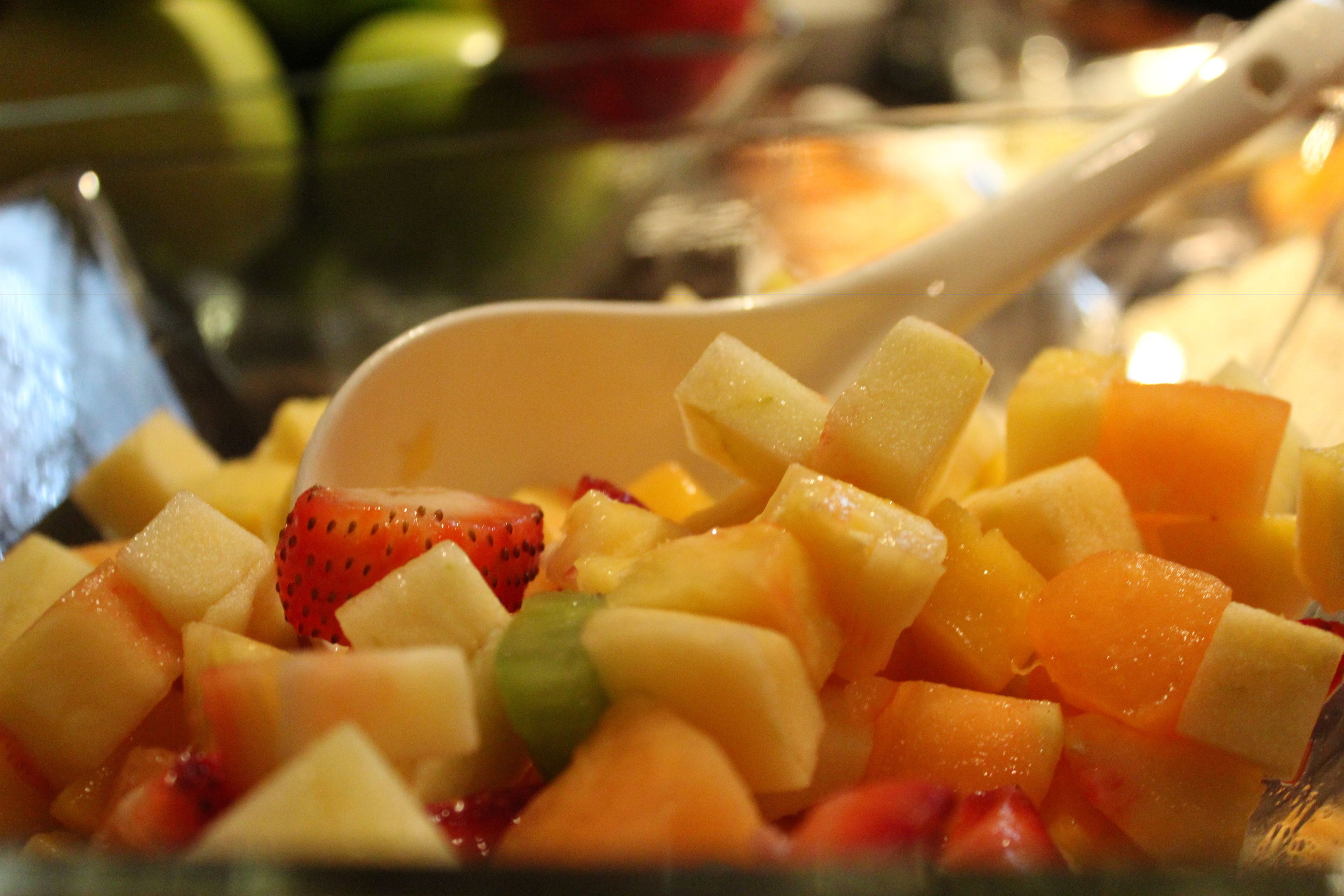 Un tazón de ensalada de frutas variadas con una cuchara.