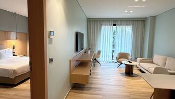 A modern hotel room with a bed, a desk, a sofa, and a TV.
