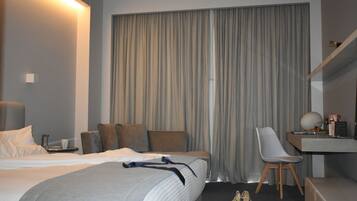 A modern hotel room with a large bed, a desk, and a chair.