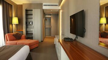 A hotel room with a bed, a sofa, a TV, a desk, and a wardrobe.