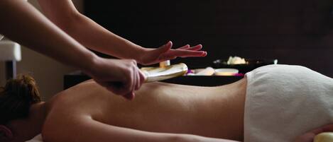A person receiving a massage with a towel covering their lower body.