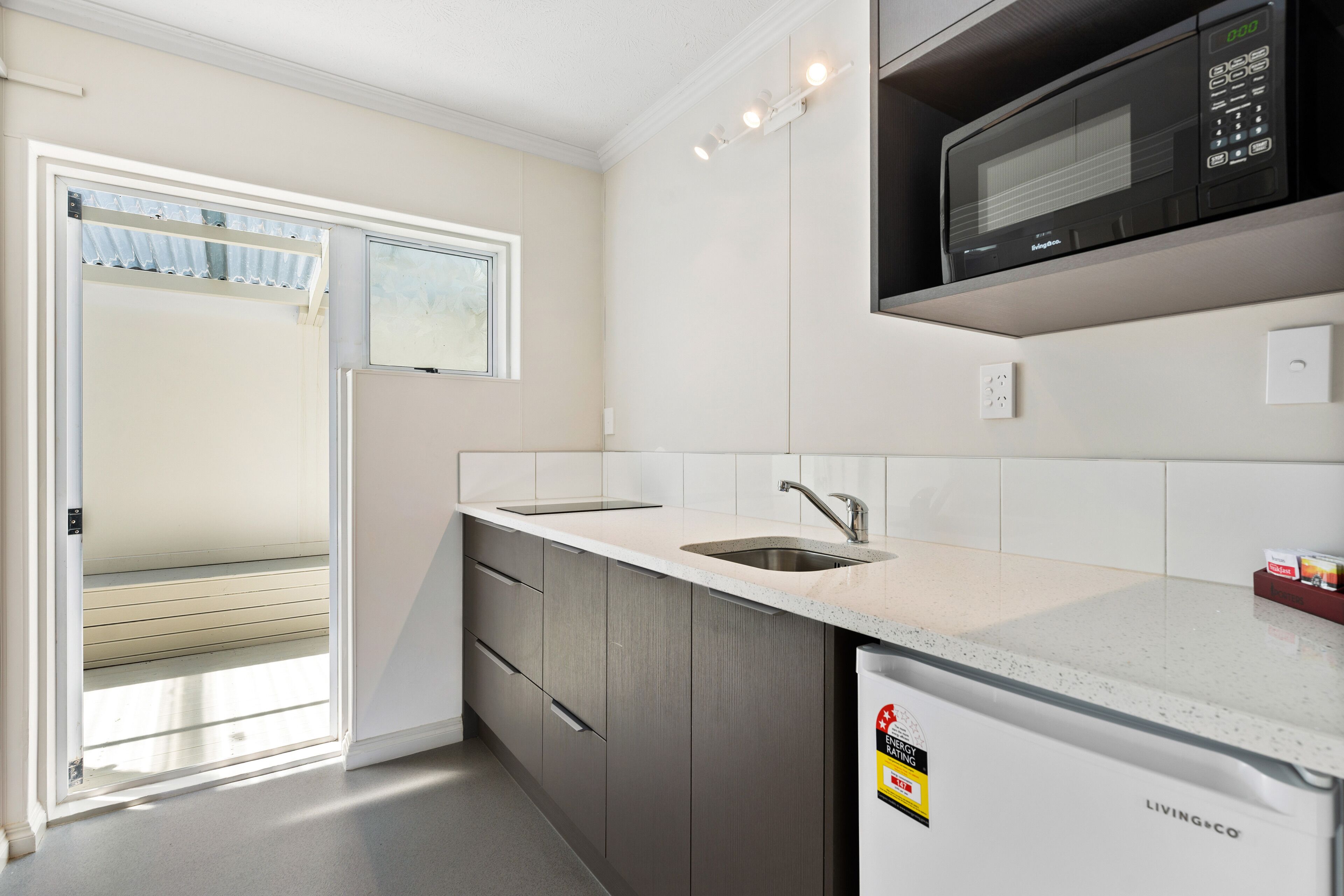A modern kitchen with a built-in microwave, a sink, and a refrigerator.