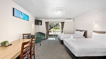 A hotel room with two beds, a desk, a chair, a TV, and a window with curtains.