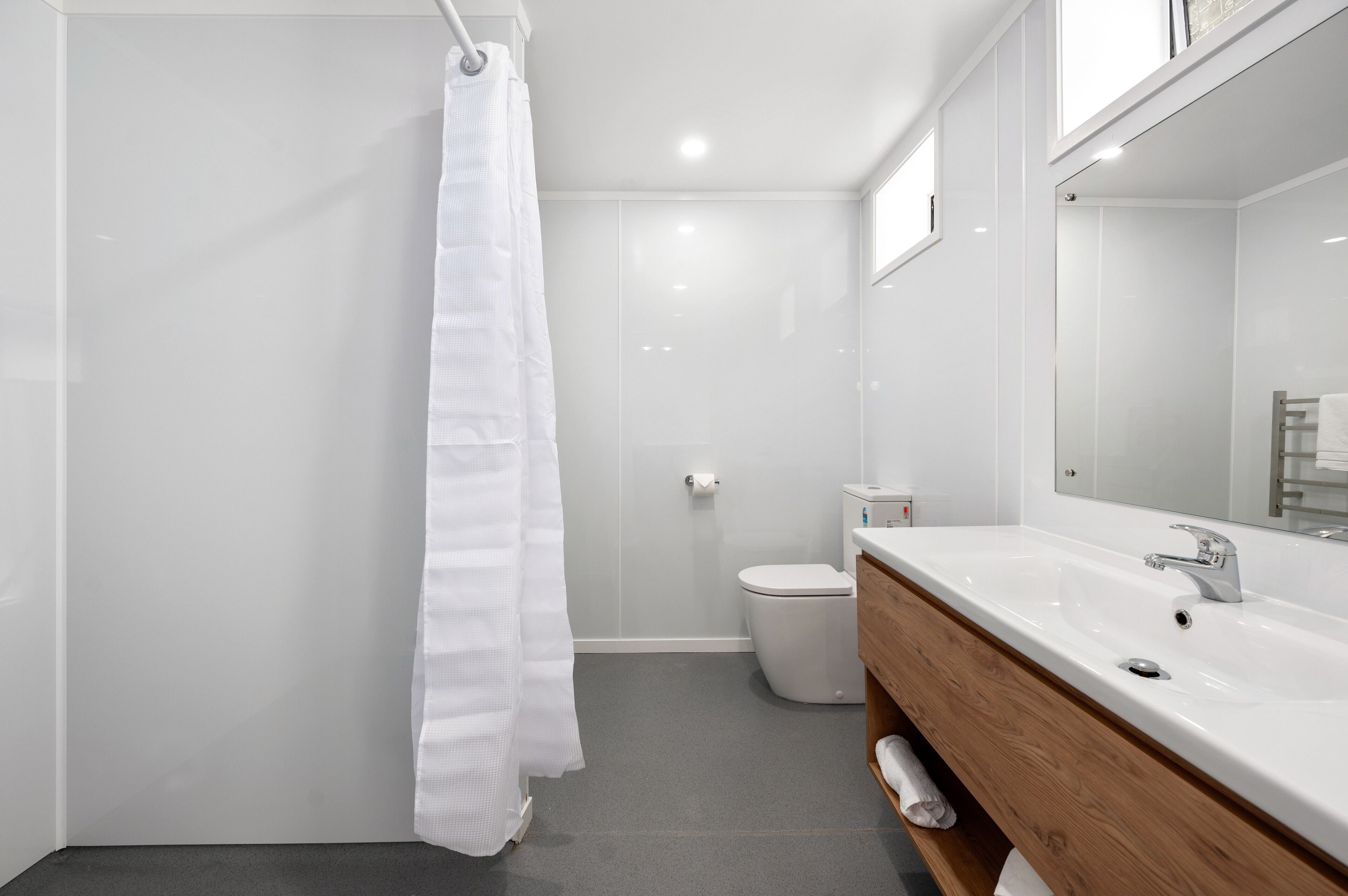 A modern bathroom with a shower, toilet, and a vanity with a mirror.