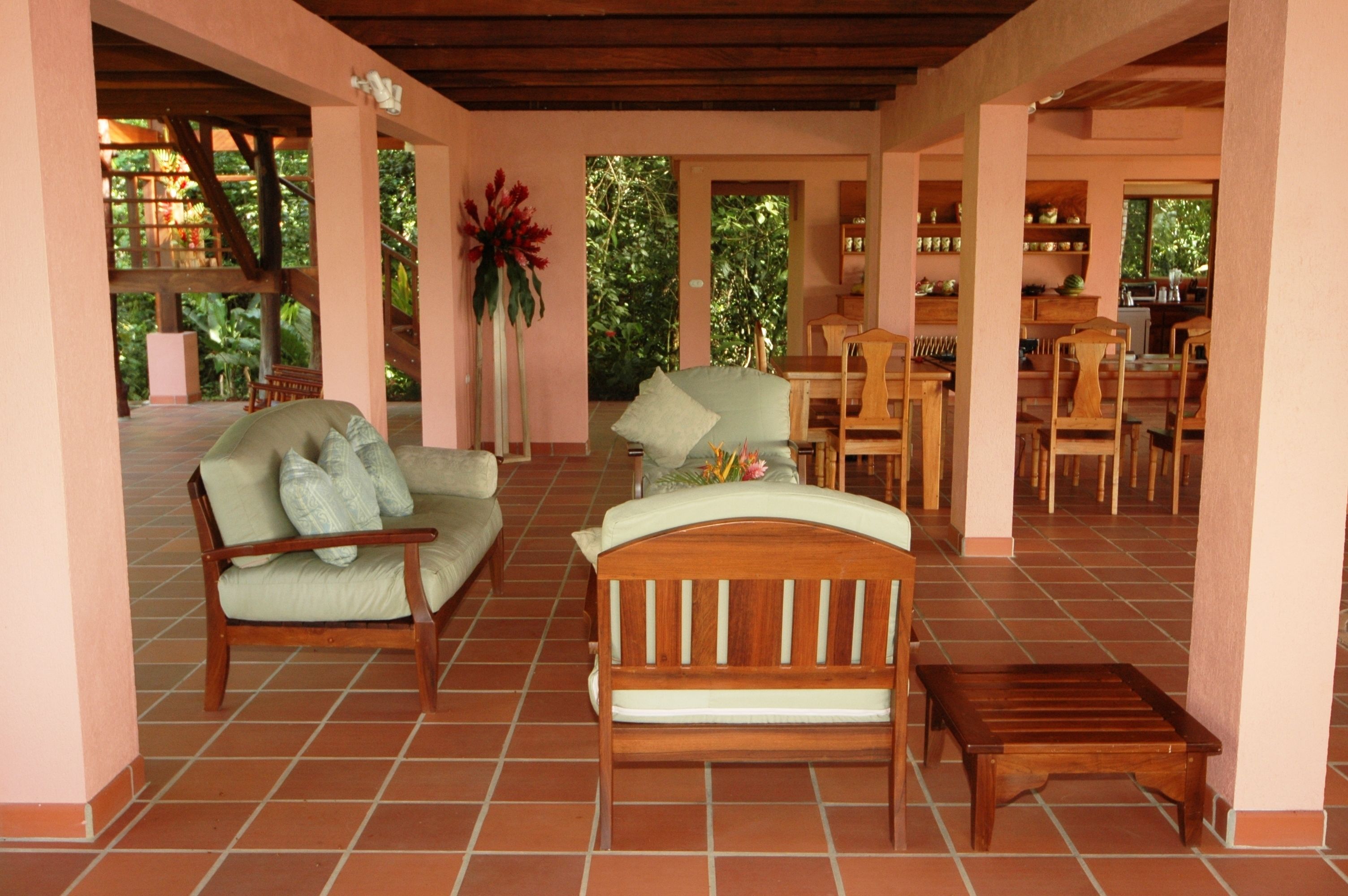 Un amplio patio con un banco de madera, un sofá con cojines y una mesa de comedor.