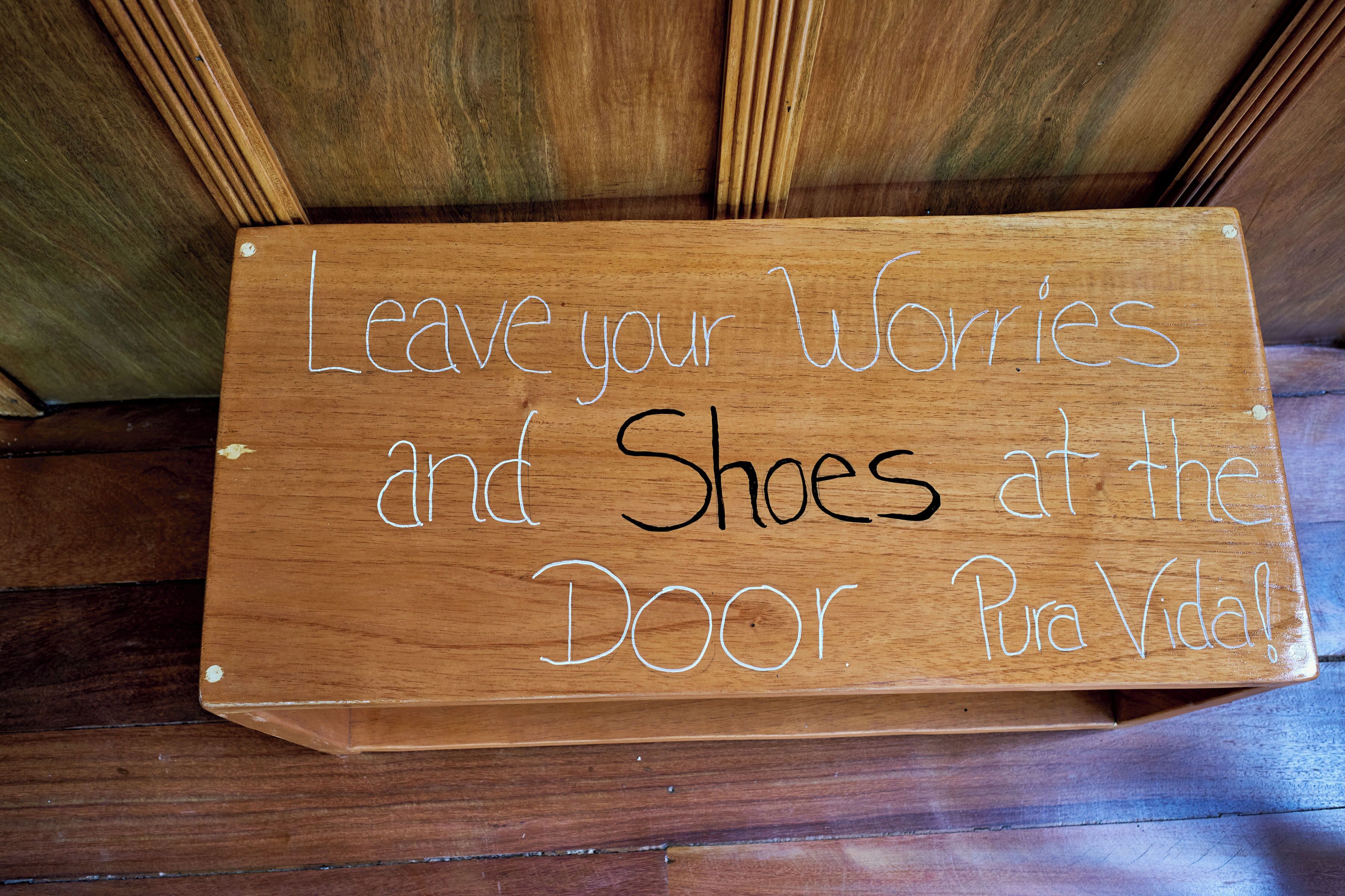 Une pancarte en bois portant l’inscription : « Laissez vos soucis et vos chaussures à la porte, profitez de la vie ! »
