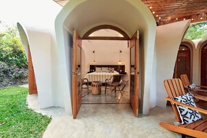 Un dormitorio de concepto abierto con cama, sillas y una mesita.