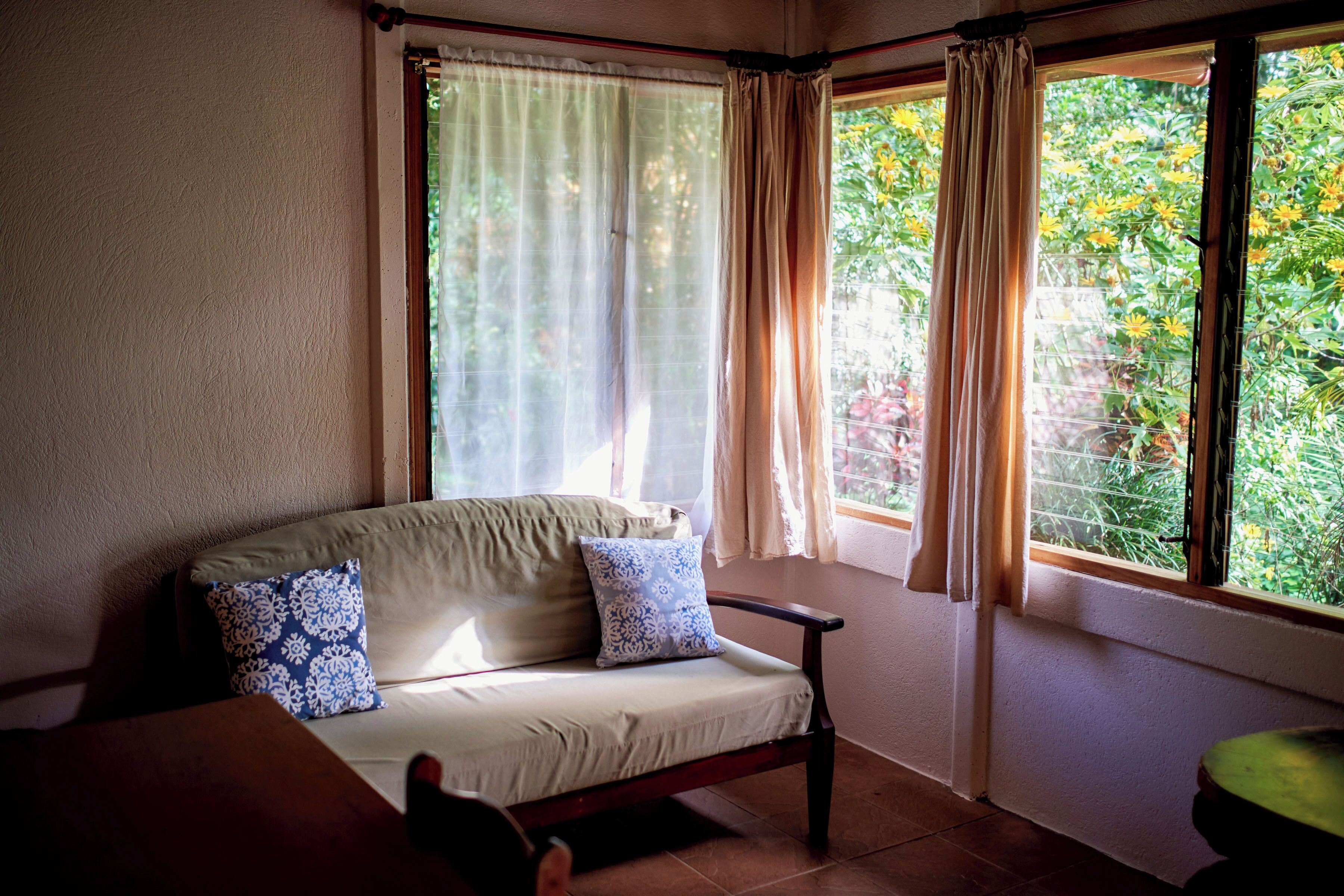 A room with a sofa, a small table, and a window with curtains.